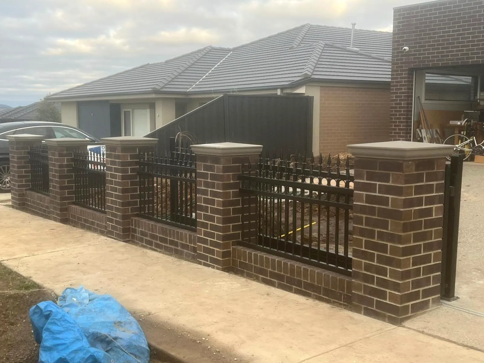 Brick front fence with piers and black steel gates